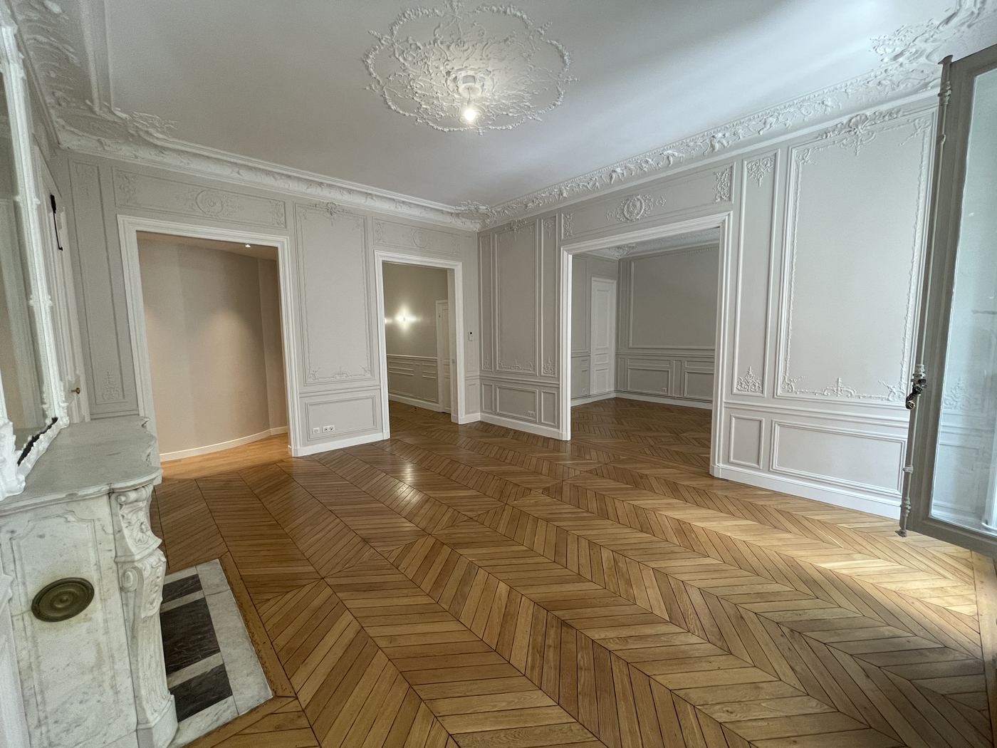 Salon haussmannien rénové avec moulures, cheminée en marbre et parquet en point de Hongrie